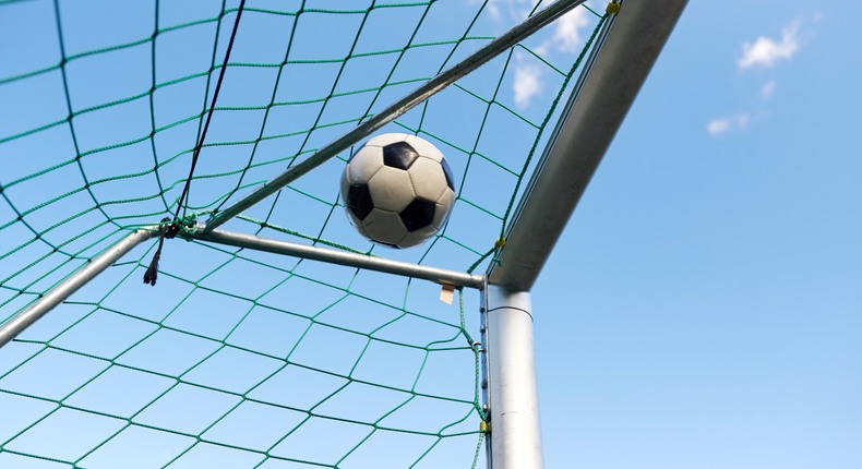 En fotboll går i mål mot en blå himmel
