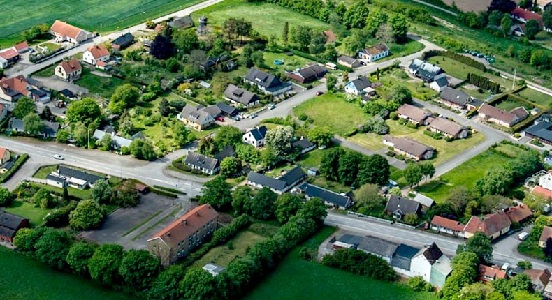 Flygbild över Östra Vemmerlöv. Friliggande villor, verksamhetshus, flerbostadshus med tomter och träd och tillhörande gator. Gröna fält omfamnar bebyggelsen.